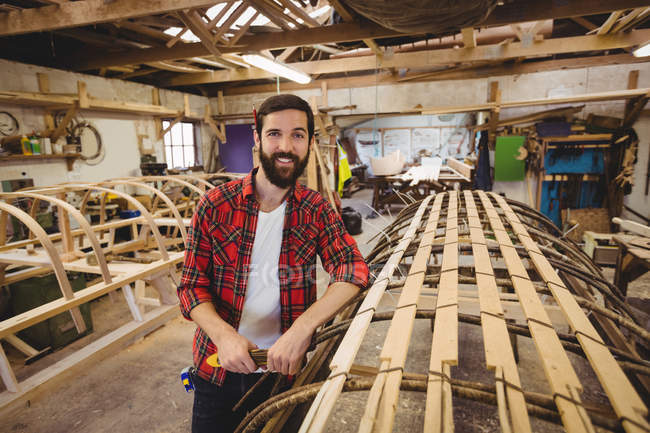 Portrait d'homme debout près d'un cadre de bateau en bois au chantier naval — Photo de stock