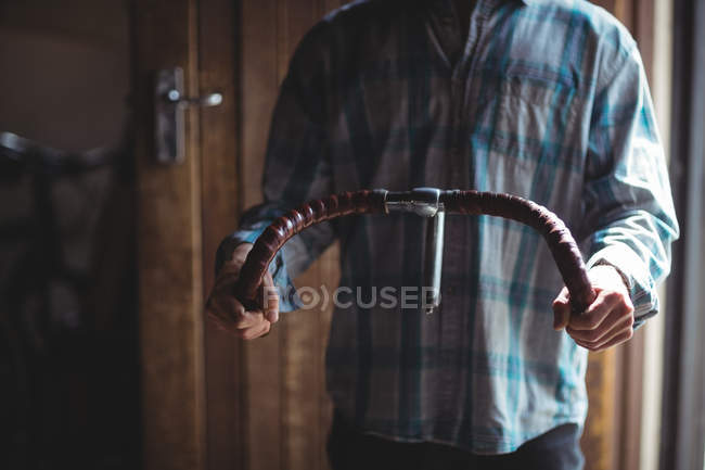 Mid-section of mechanic examining a bicycle handle bar in workshop — Stock Photo
