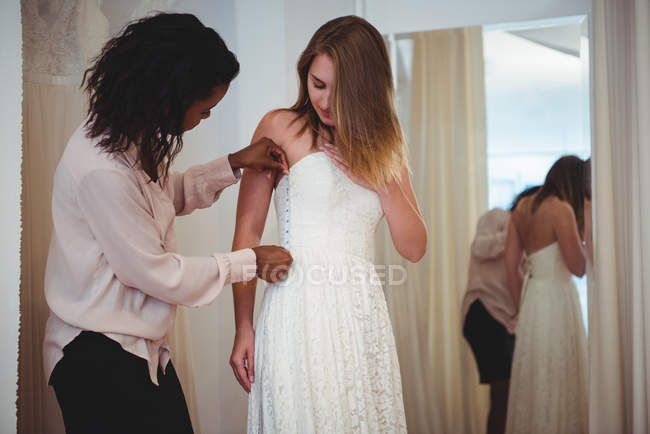 Mujer probándose el vestido de novia en un estudio con la ayuda del diseñador de moda - foto de stock