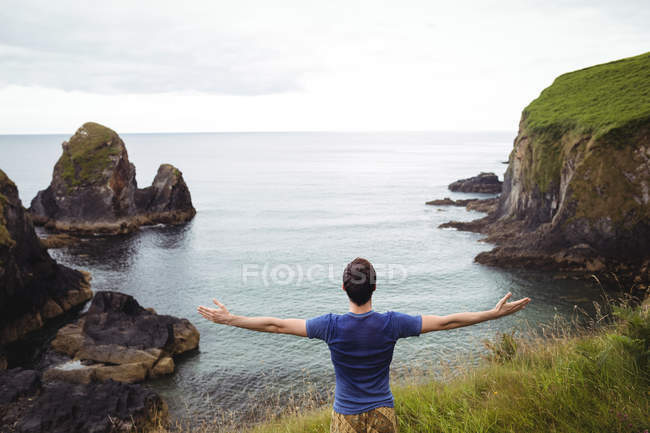 Вид сзади человека, стоящего с вытянутыми на скале руками — стоковое фото