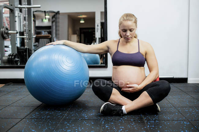 Pregnant woman holding her belly in gym — Stock Photo
