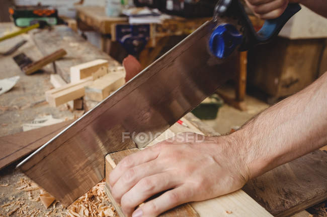 Man cutting a wooden plank at boatyard — Stock Photo