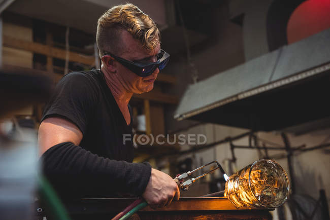Ventilador de vidro dando toque final ao pedaço de vidro com tocha de sopro de vidro na fábrica de sopro de vidro — Fotografia de Stock