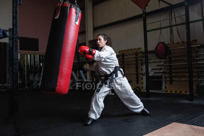 Side view of Woman practicing karate with punching bag in fitness studio — Stock Photo
