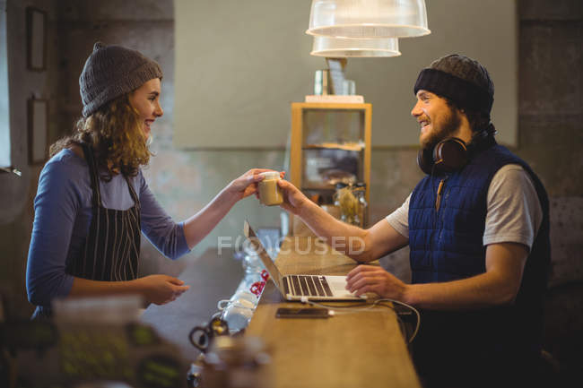 Waitress serving coffee to mechanic at counter in workshop — Stock Photo