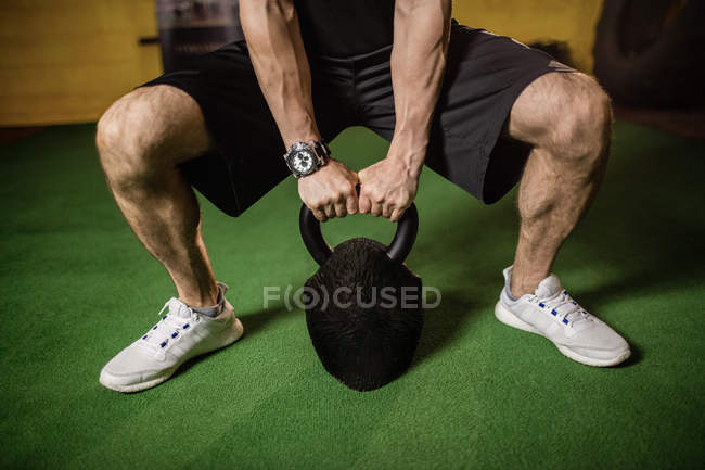 Cropped image of sportsman lifting weight in gym — Stock Photo