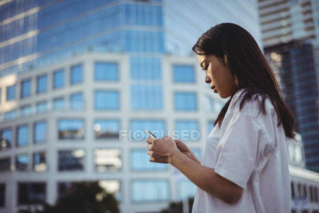 Mulher jovem mensagens de texto no telefone celular na rua — Fotografia de Stock