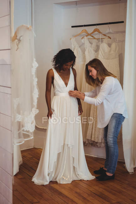 Жінка намагається на весільній сукні в студії за допомогою дизайнера моди — стокове фото