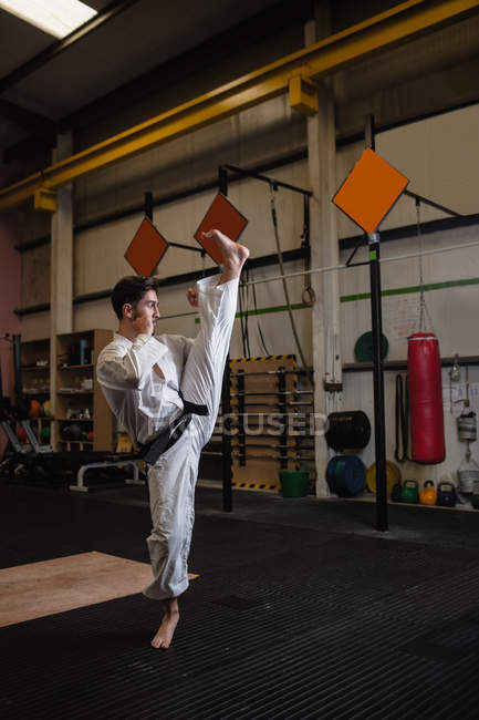 Вид сбоку на человека, практикующего каратэ в фитнес-студии — стоковое фото