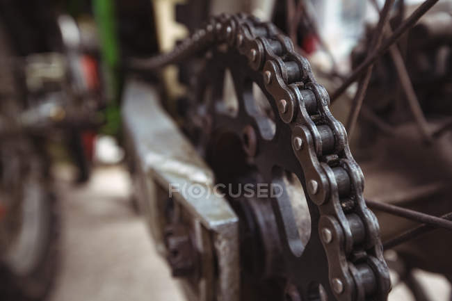 Primer plano de la cadena de motocicletas en taller mecánico industrial - foto de stock