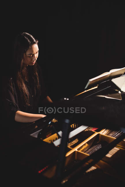 Beautiful woman playing a piano in music studio — Stock Photo