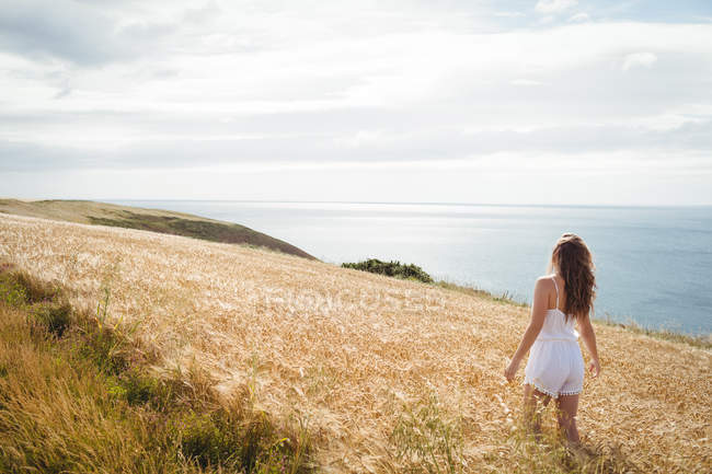 Visão traseira da mulher em pé no campo de trigo no dia ensolarado — Fotografia de Stock