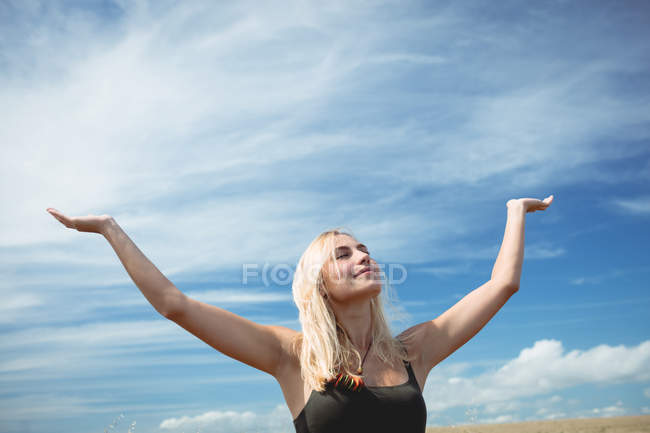 Schöne blonde Frau steht mit offenen Armen auf dem Feld — Stockfoto