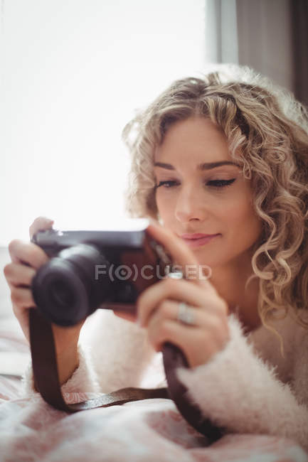 Mulher olhando para câmera digital no quarto em casa — Fotografia de Stock