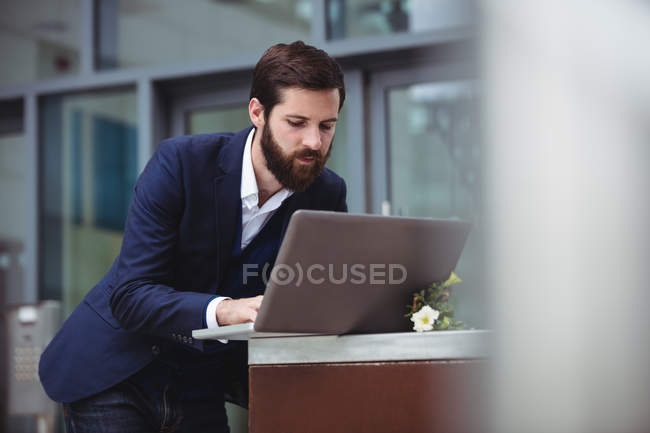 Attentive businessman using laptop outside office — Stock Photo