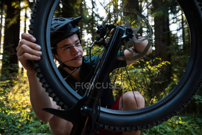 Homme cycliste réparer son vélo dans la forêt par une journée ensoleillée — Photo de stock