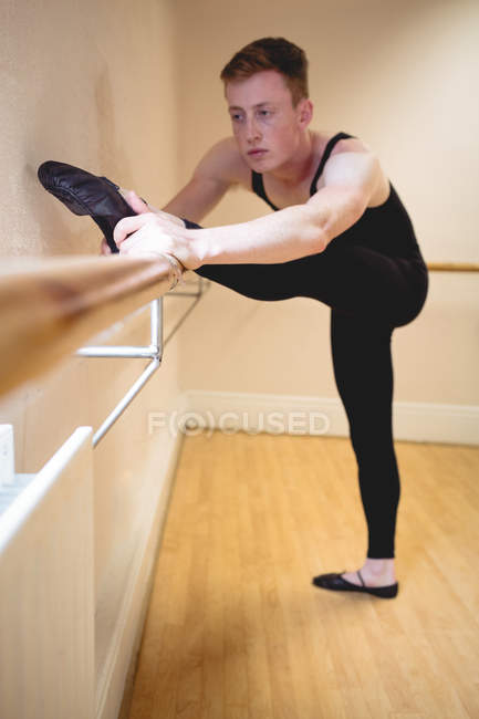 Selective focus of Ballerino stretching on barre while practicing ballet dance in studio — Stock Photo