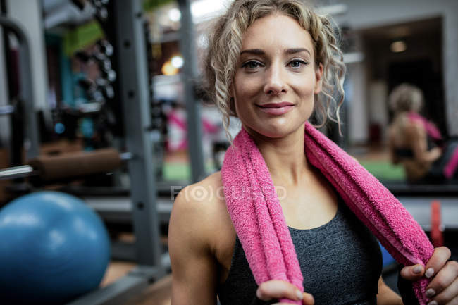 Retrato de una hermosa mujer con una toalla alrededor de su cuello en el gimnasio - foto de stock