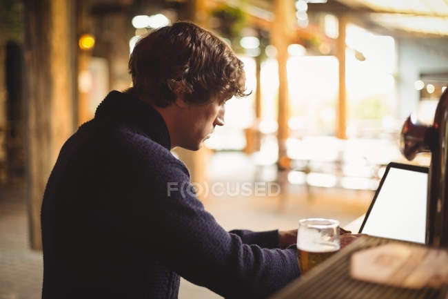 Man using laptop at bar — Stock Photo