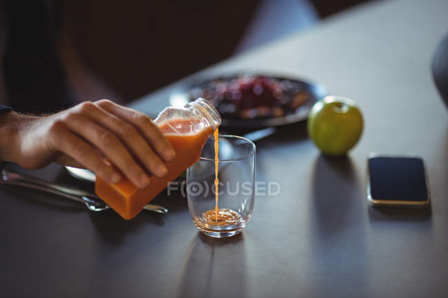 Primo piano di mano versando il succo in vetro — Foto stock