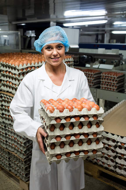 Retrato del personal femenino sosteniendo bandejas de huevo en fábrica - foto de stock