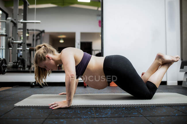 Pregnant woman doing push-ups in gym — Stock Photo