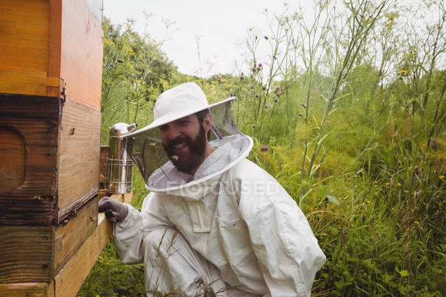 Apiculteur utilisant fumeur d'abeilles dans le champ — Photo de stock