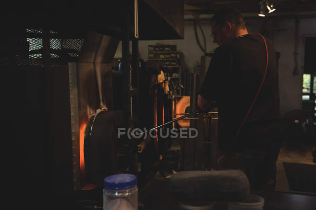 Стеклодувка нагревательного стекла в печи на стекольном заводе — стоковое фото