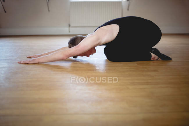 Вид сбоку на Балерино, выполняющего упражнения на растяжку в студии — стоковое фото