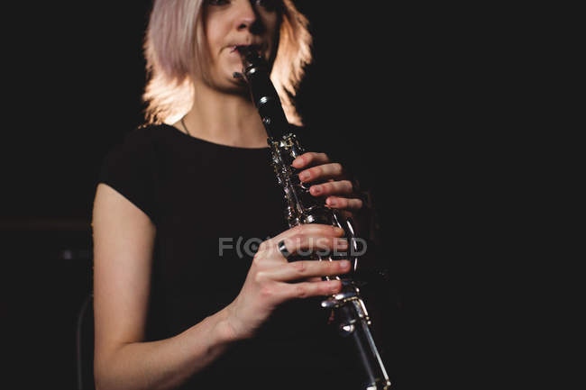Hermosa mujer tocando un clarinete en la escuela de música - foto de stock