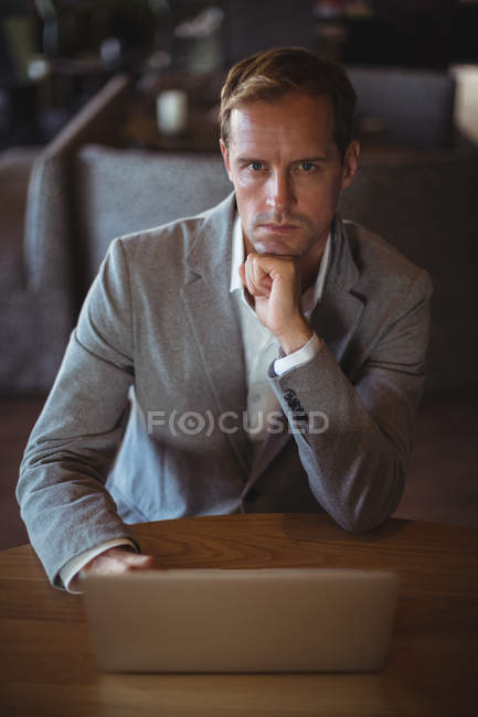 Retrato de empresario confiado usando el ordenador portátil en la cafetería - foto de stock