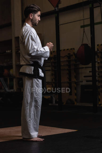 Vue latérale de l'homme pratiquant le karaté dans un studio de fitness sombre — Photo de stock