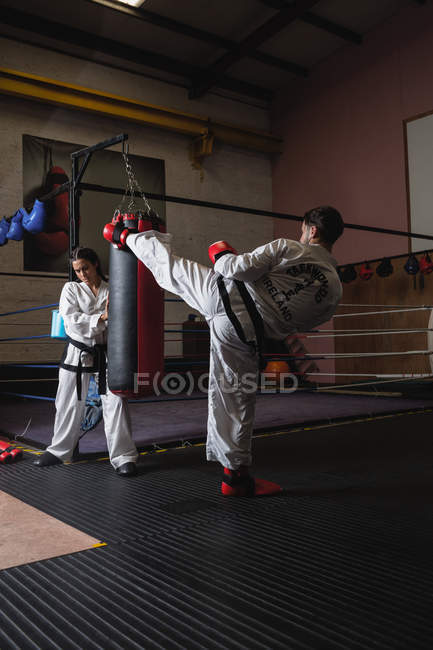Man and woman practicing karate with punching bag in studio — Stock Photo