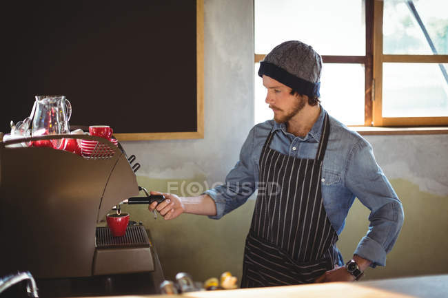 Waiter making cup of coffee at counter in workshop — Stock Photo