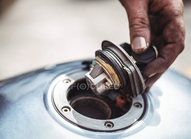 Hand of mechanic opening a fuel tank of motor bike at workshop — Stock Photo