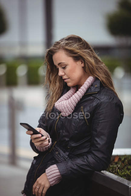 Mulher bonita usando jaqueta de couro e usando smartphone na rua — Fotografia de Stock