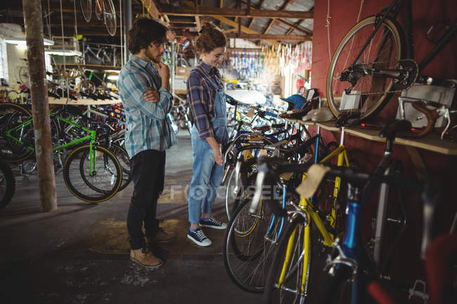 Mecânica examinando uma bicicleta em oficina de bicicleta — Fotografia de Stock