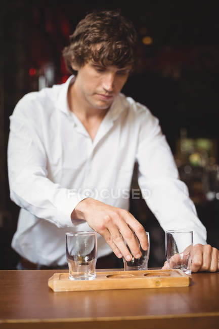 Barman organizando copo de cerveja na bandeja no balcão do bar no bar — Fotografia de Stock