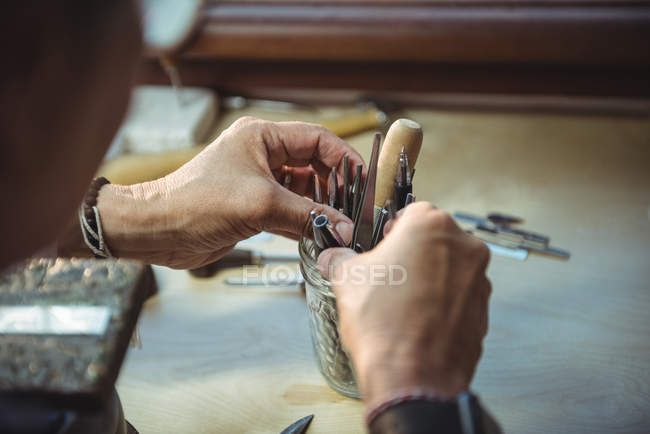 Close-up of craftswoman holding various tools in workshop — Stock Photo