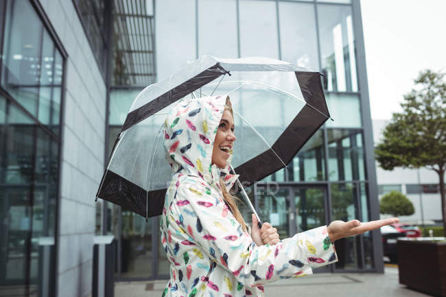 Vista lateral da mulher bonita feliz segurando guarda-chuva durante a estação chuvosa — Fotografia de Stock
