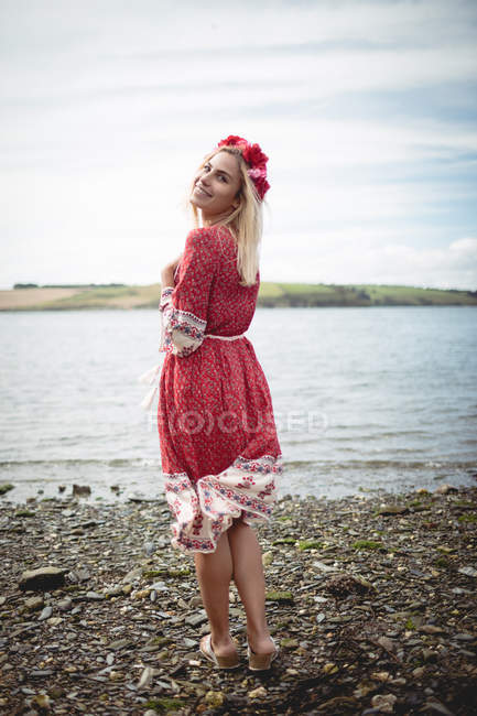 Rückansicht einer glücklichen blonden Frau, die ein Blumen-Diadem trägt und in der Nähe des Flusses steht — Stockfoto