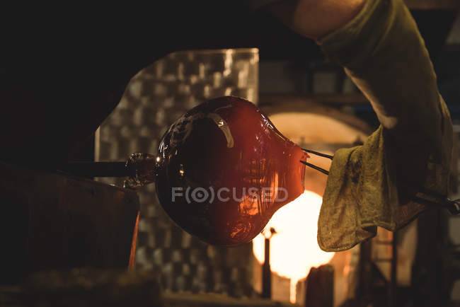 Soplador de vidrio pieza de calefacción de vidrio en el horno en la fábrica de soplado de vidrio - foto de stock