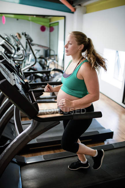 Femme enceinte faisant de l'exercice sur tapis roulant au gymnase — Photo de stock
