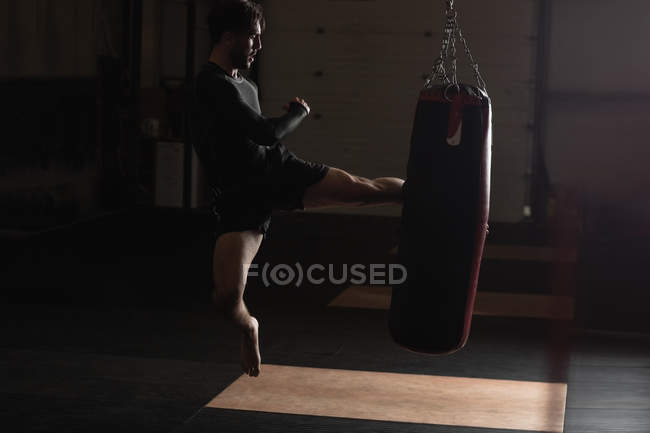 Side view of Boxer practicing boxing with punching bag in fitness studio — Stock Photo