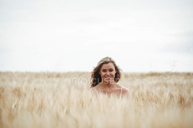 Портрет улыбающейся женщины, стоящей на пшеничном поле в солнечный день — стоковое фото
