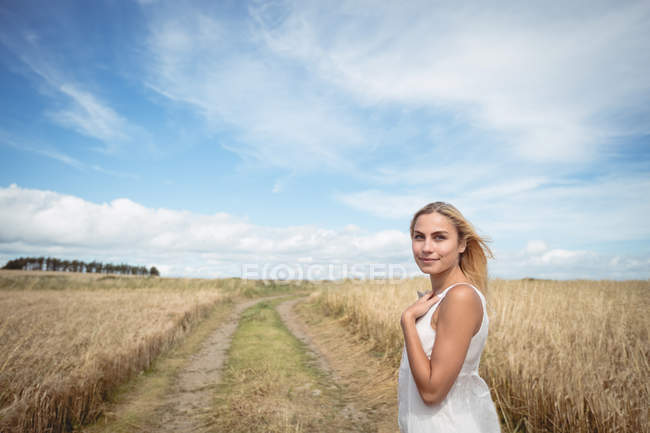 Красива блондинка стоїть в полі і дивиться на камеру — стокове фото