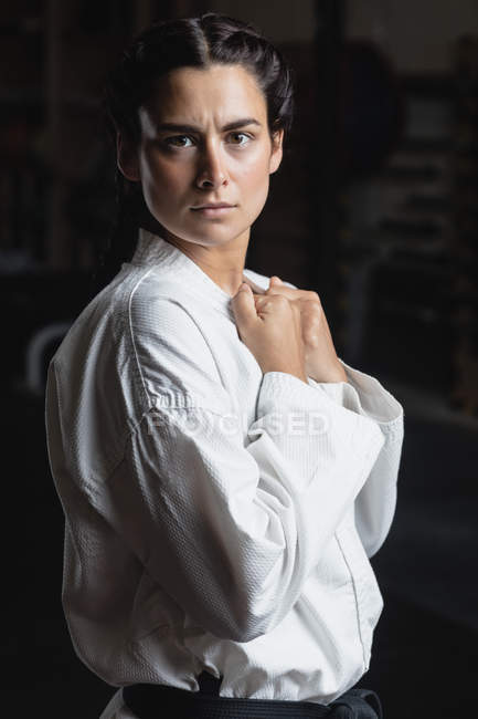 Portrait of woman in karate kimono standing in fitness studio and looking at camera — Stock Photo