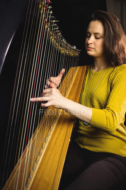 Aufmerksame Frau spielt Harfe in Musikschule — Stockfoto