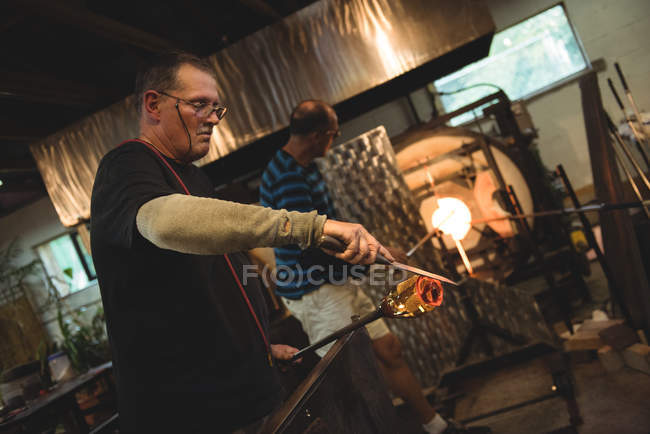 Équipe de souffleurs de verre chauffant le verre dans le four à l'usine de soufflage du verre — Photo de stock