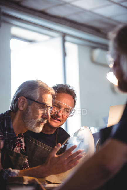 Glassblowers interacting while examining glassware in glassblowing factory — Stock Photo